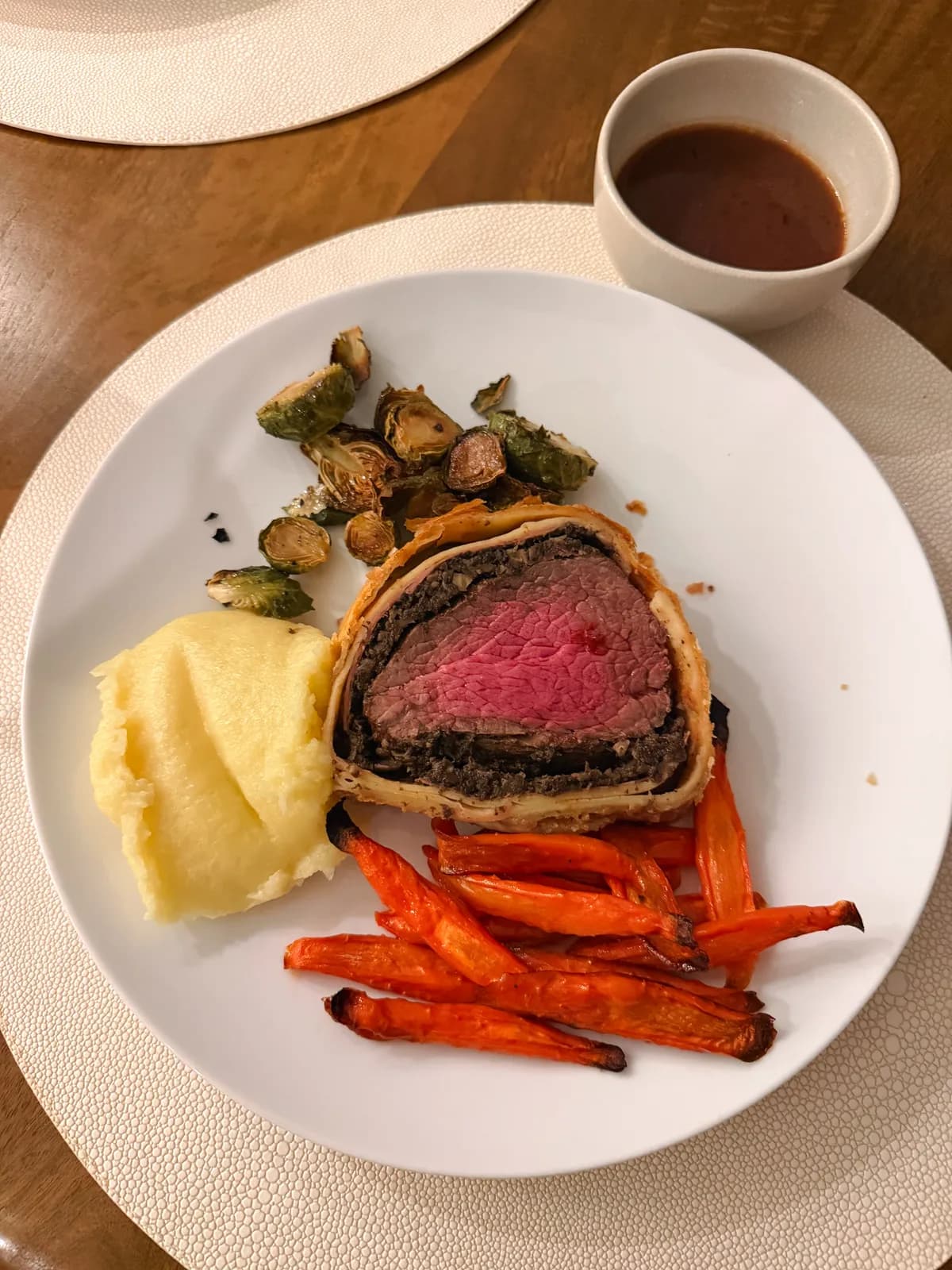 Sliced beef wellington with a golden pastry crust on a wooden board