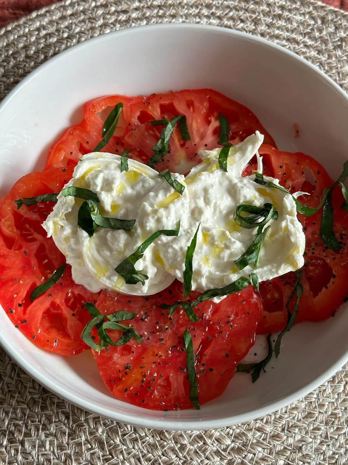 A creamy burrata plated with tomatoes and olive oil