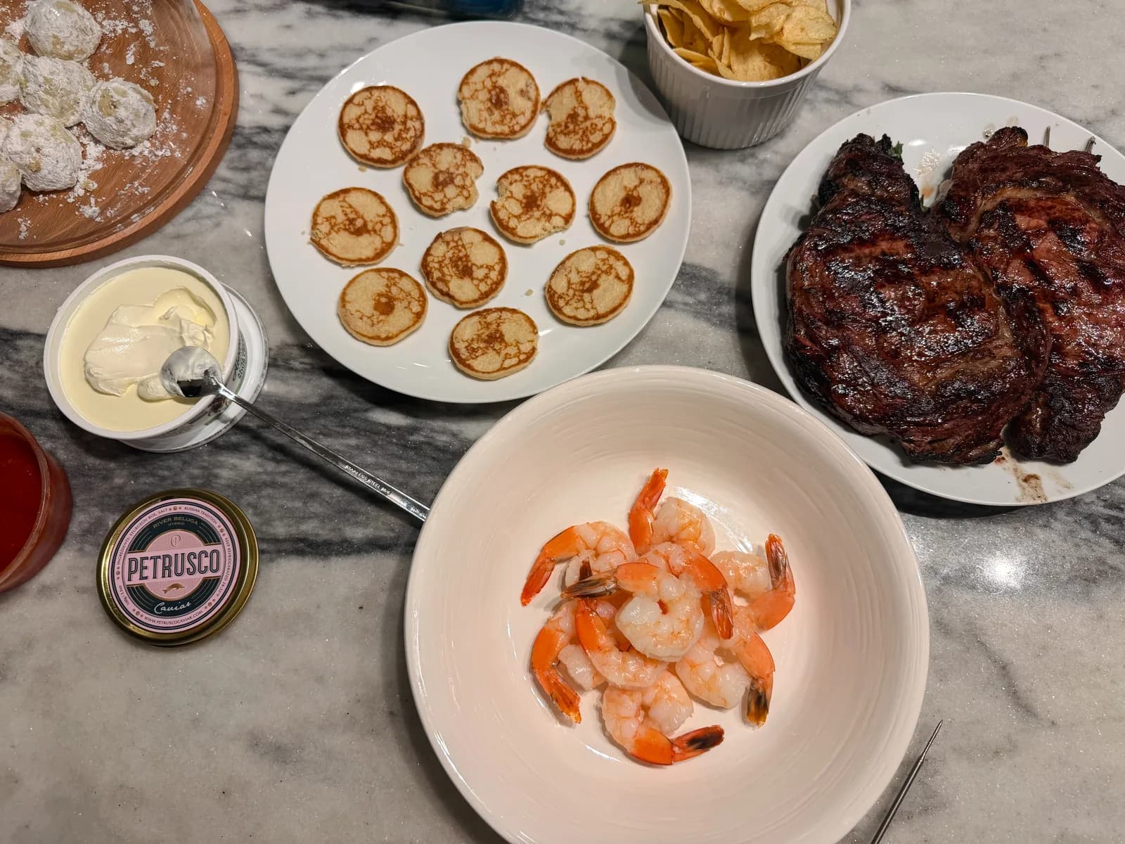 A snack board with caviar, blinis, crème fraîche, and chopped egg