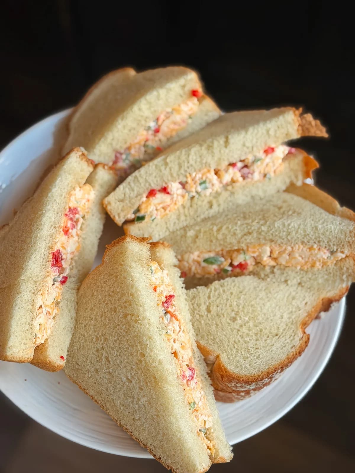 Pimento cheese sandwiches cut into triangles on a tea towel