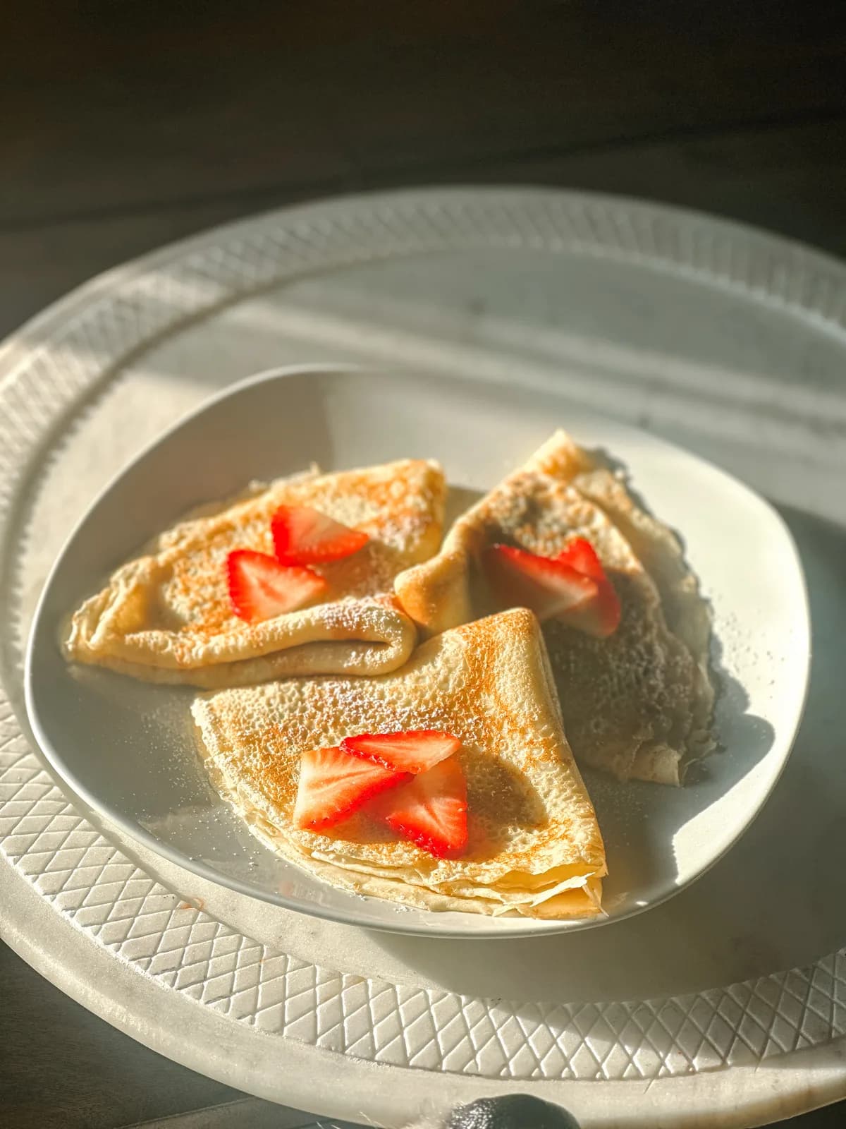 Folded crepes with macerated strawberries and powdered sugar