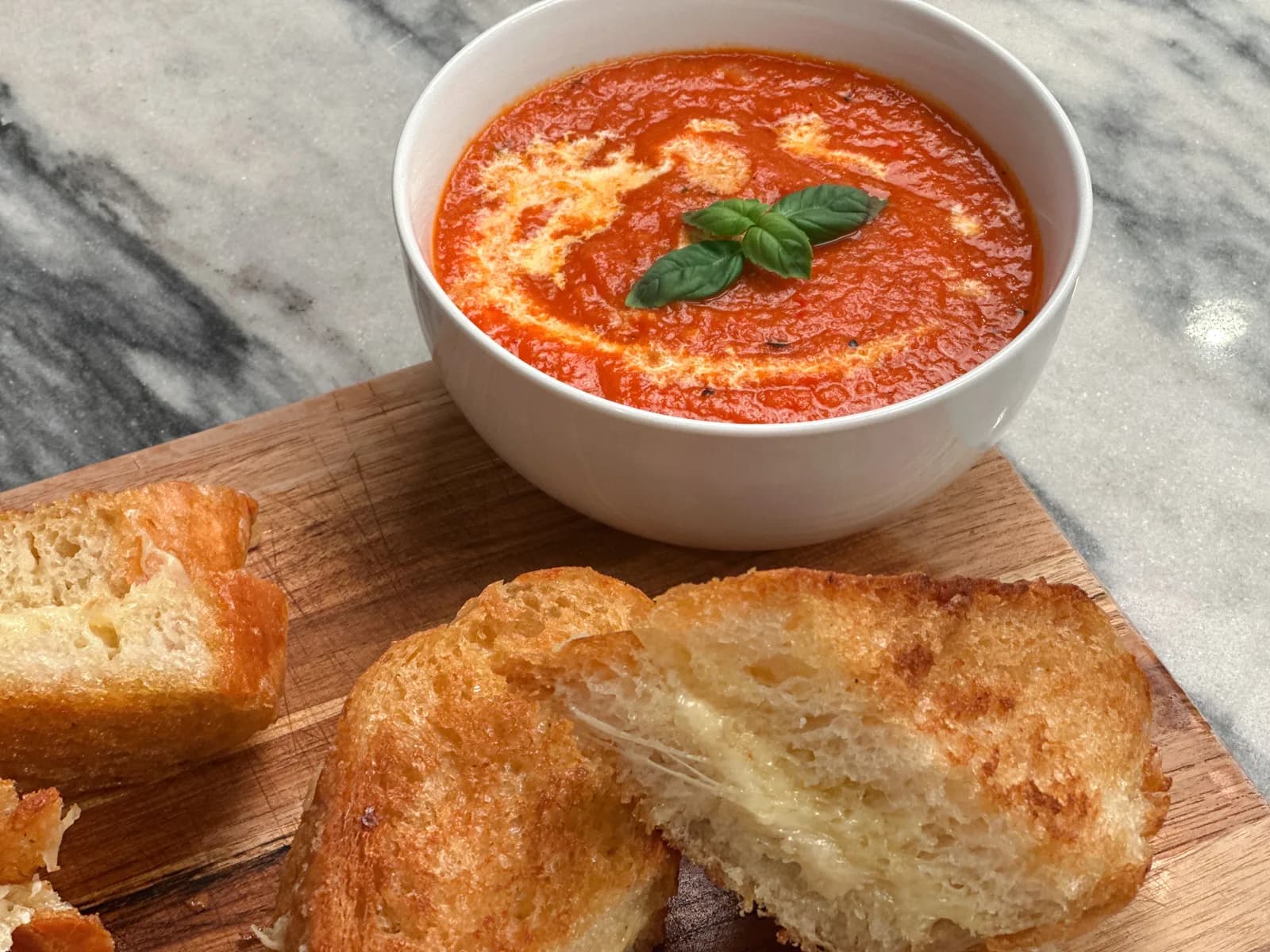 A bowl of creamy tomato bisque with a swirl of cream and herbs